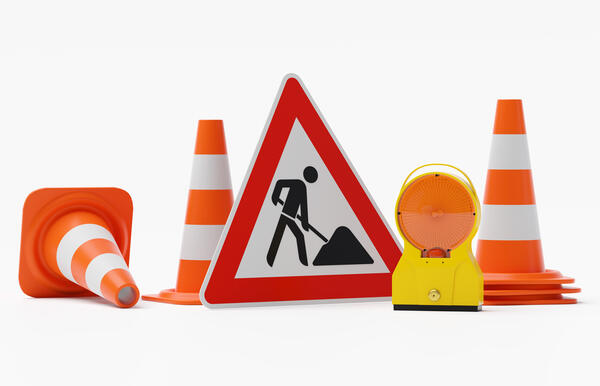 Baustelle Warnung - Bakenleuchte Baustellenleuchte Gehäuse gelb - Glas orange mit Schild Baustelle und mehreren Verkehrshütchen - freigestellt